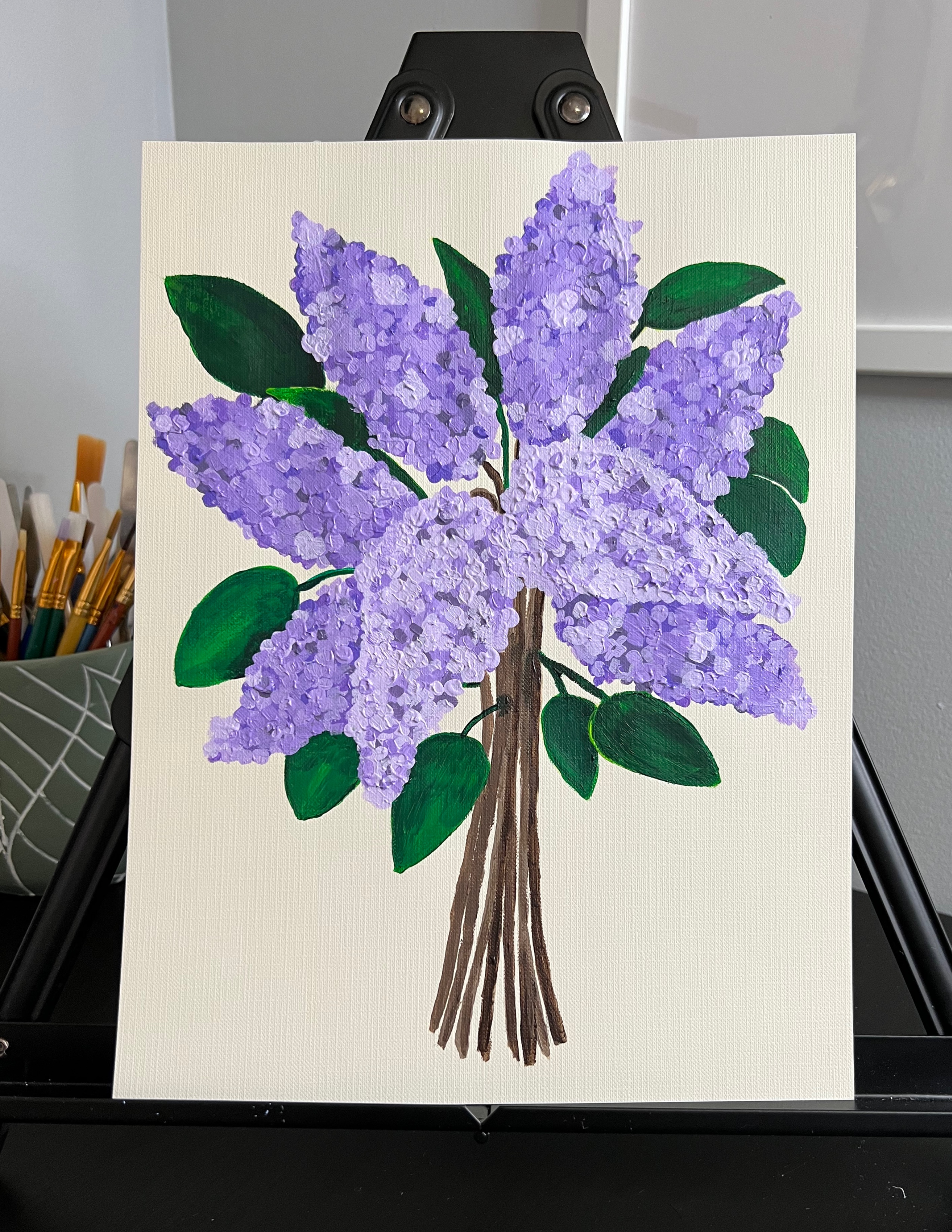 painting of a bunch of purple lilacs, with green leaves and stems 